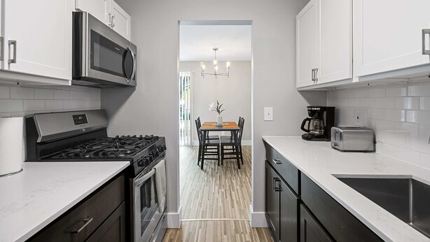 A modern kitchen with white cabinets, a stainless steel microwave, a gas stove, and a toaster. - Bright and Airy 2BR 2BA in the Heart of the City (Rochester)