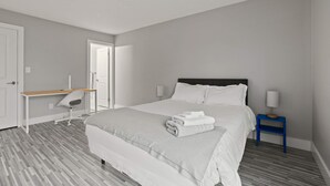 A modern hotel room with a large bed, a desk, and a nightstand. - Comfy 2BR 2BA Unit in Pime Location (Rochester)