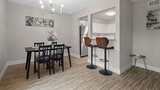 Une cuisine moderne avec des meubles blancs, un réfrigérateur en acier inoxydable et un coin bar équipé de tabourets.