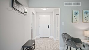 A hallway with a bench, a chair, a wall-mounted sign, and two framed artworks. - 2-bedroom Spacious Stay (Rochester)