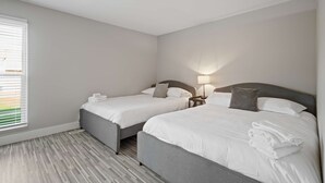 A hotel room with two beds, a bedside table with a lamp, and a window with blinds. - 2-bedroom Spacious Stay (Rochester)