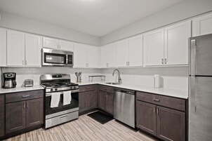 A modern kitchen with stainless steel appliances, white cabinets, and a tiled backsplash.