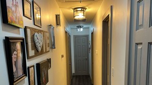 A hallway with framed pictures on the walls, a wooden floor, and a door at the end. - Great Place to Stay When Visiting - Pet Friendly (Rushville)