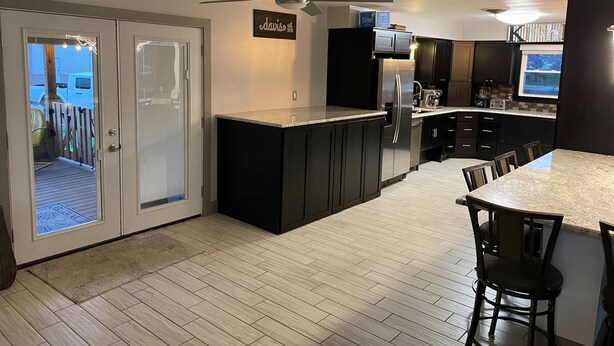 A modern kitchen with dark cabinetry, a stainless steel refrigerator, and a ceiling fan. - Great Place to Stay When Visiting - Pet Friendly (Rushville)
