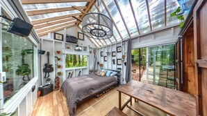 Une pièce confortable et bien éclairée, avec un lit, une table en bois et une grande fenêtre donnant sur l’extérieur.