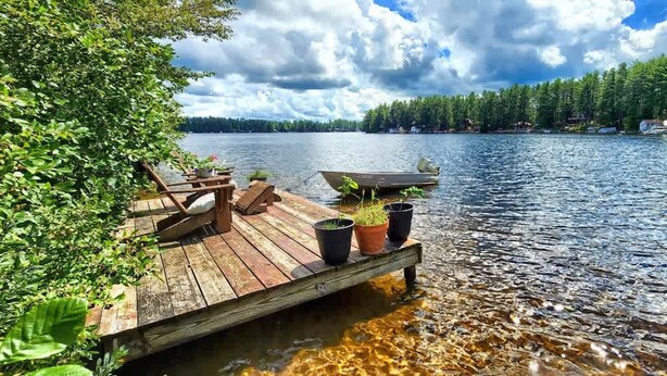 Une jetée en bois s’avançant dans un lac, avec un bateau amarré à son extrémité.