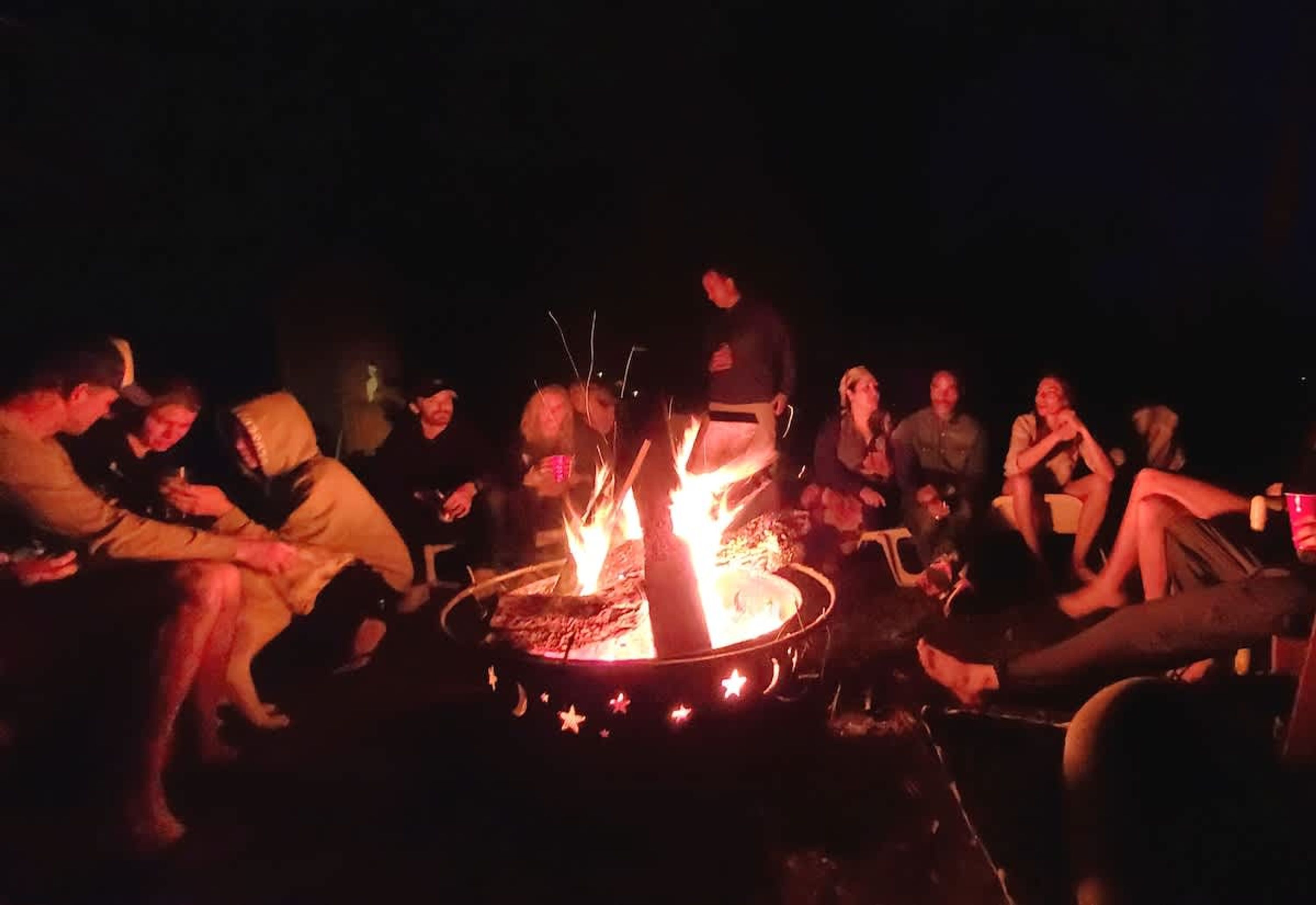 A group of people gathered around a campfire at night.