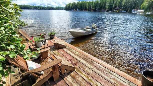 A wooden dock extending into a lake with a small boat moored at the end.