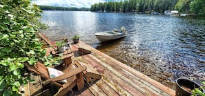 Une jetée en bois s’avance sur un lac, et une petite barque est amarrée à son extrémité.