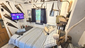 A room with a bed, a television, and various tools and equipment on the walls.