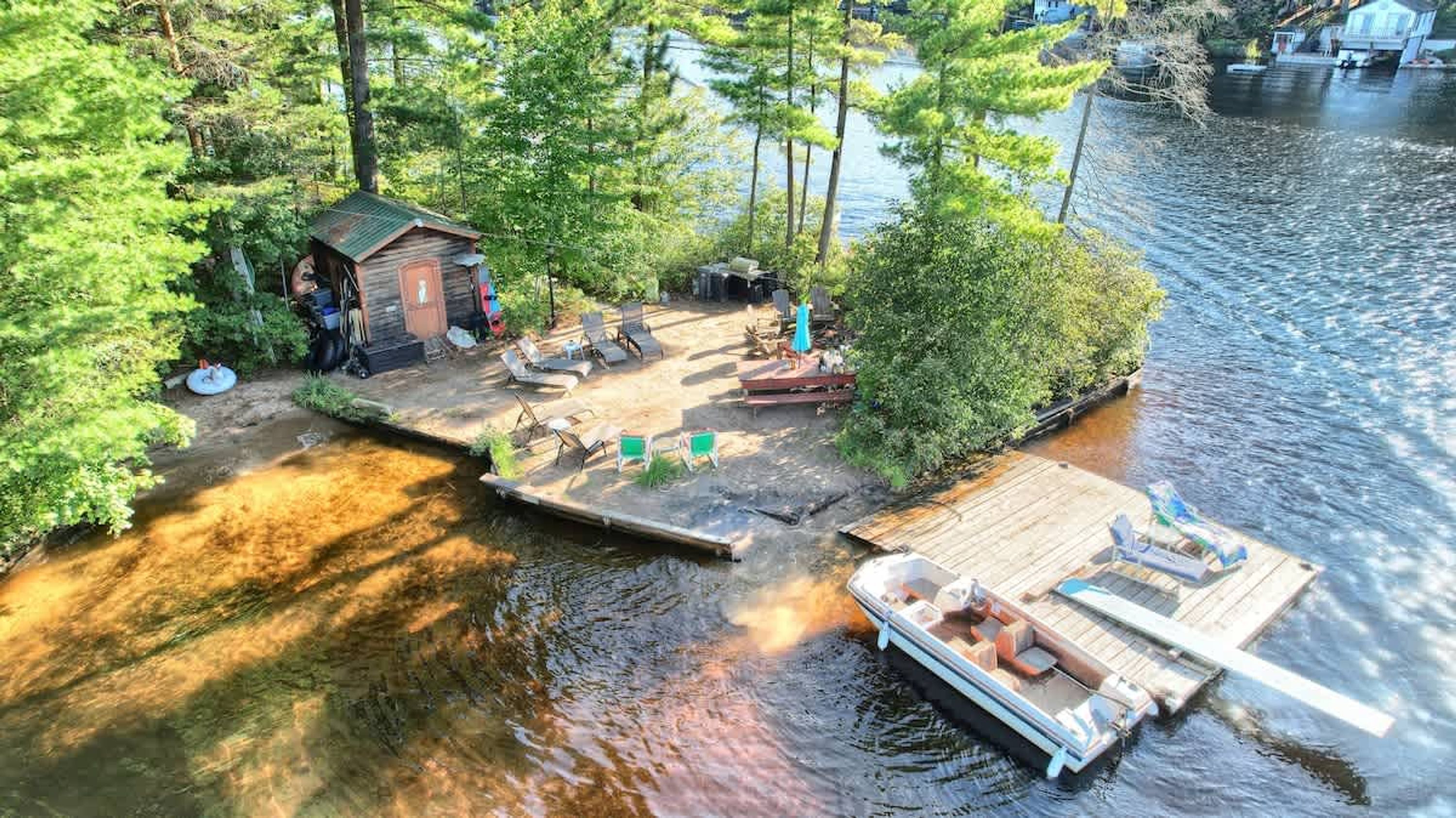 A lakeside cabin with a dock, outdoor seating, and a small boat.