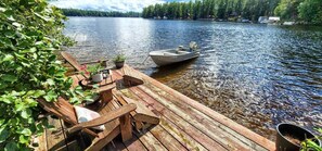 A wooden dock extending into a calm lake, with a small boat moored nearby. - The Stabbin Cabin Grant Island w Boat Hottub Pet (Brantingham)
