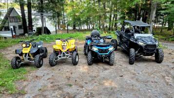Four off-road vehicles parked on a dirt path in a wooded area.