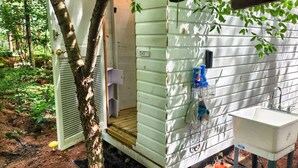 A small, single-room cabin with a wooden deck, a window, and a sink.