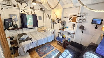 Een compacte, overzichtelijke kamer met een bed, een klein tafeltje, een wastafel en een televisie.