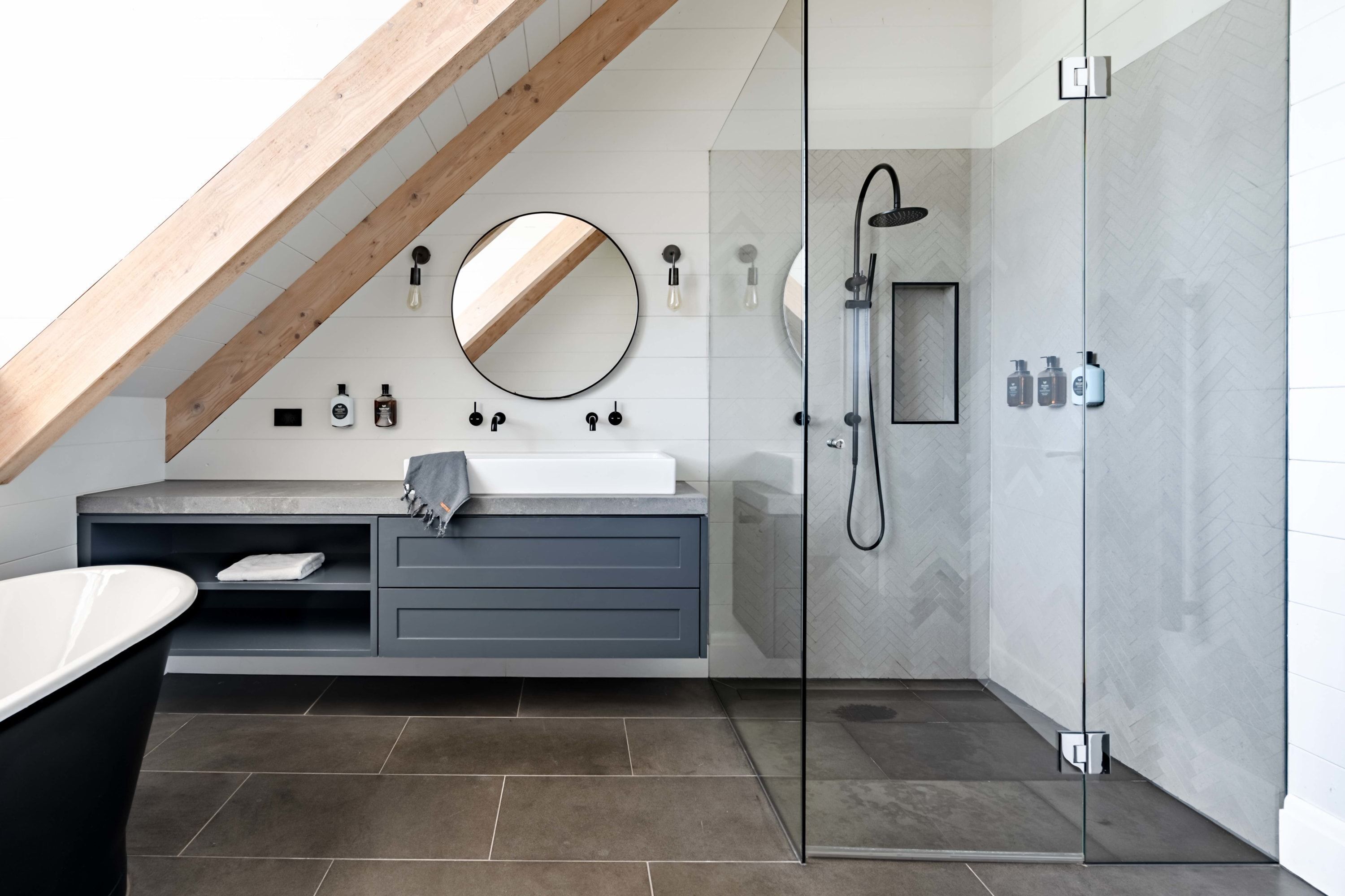 A modern bathroom with a glass-enclosed shower, a vanity with a mirror, and a bathtub.