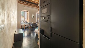 Eine Küche mit einem großen, schwarzen Kühlschrank, Holzbalken an der Decke und einem Essbereich mit Tisch und Stühlen.