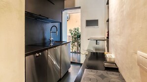 Eine moderne Küche mit Edelstahlgeräten, einer schwarzen Arbeitsplatte und Blick auf einen Außenbalkon.