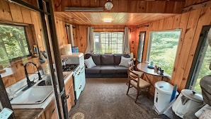 Interior acogedor de una cabaña con kitchenette, un sofá y un comedor.