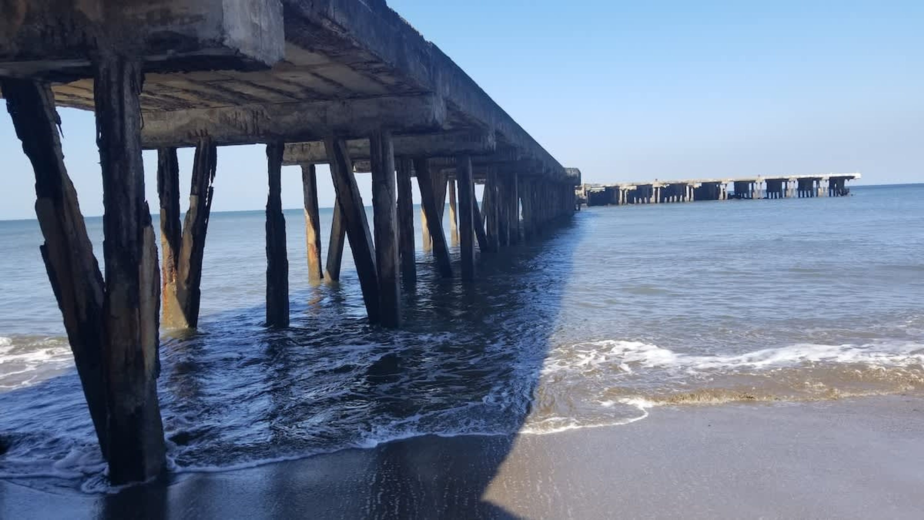 Une jetée s’avançant dans des eaux calmes, sous un ciel dégagé.
