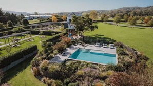 Zona residencial com piscina, quadra de tênis e jardim bem cuidado.