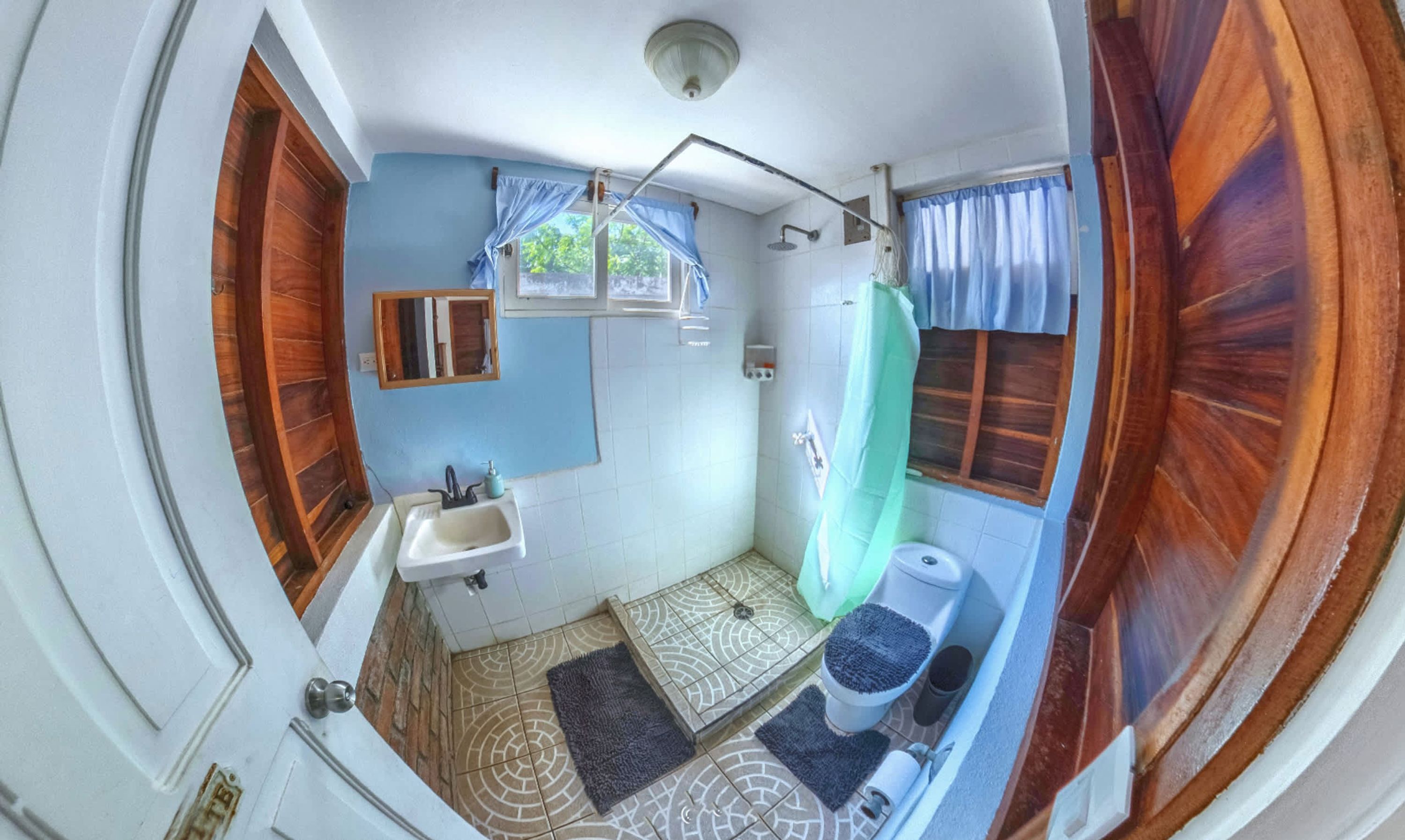 Un baño con lavamanos, espejo, ducha e inodoro.