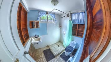 Un baño con lavamanos, espejo, ducha e inodoro.