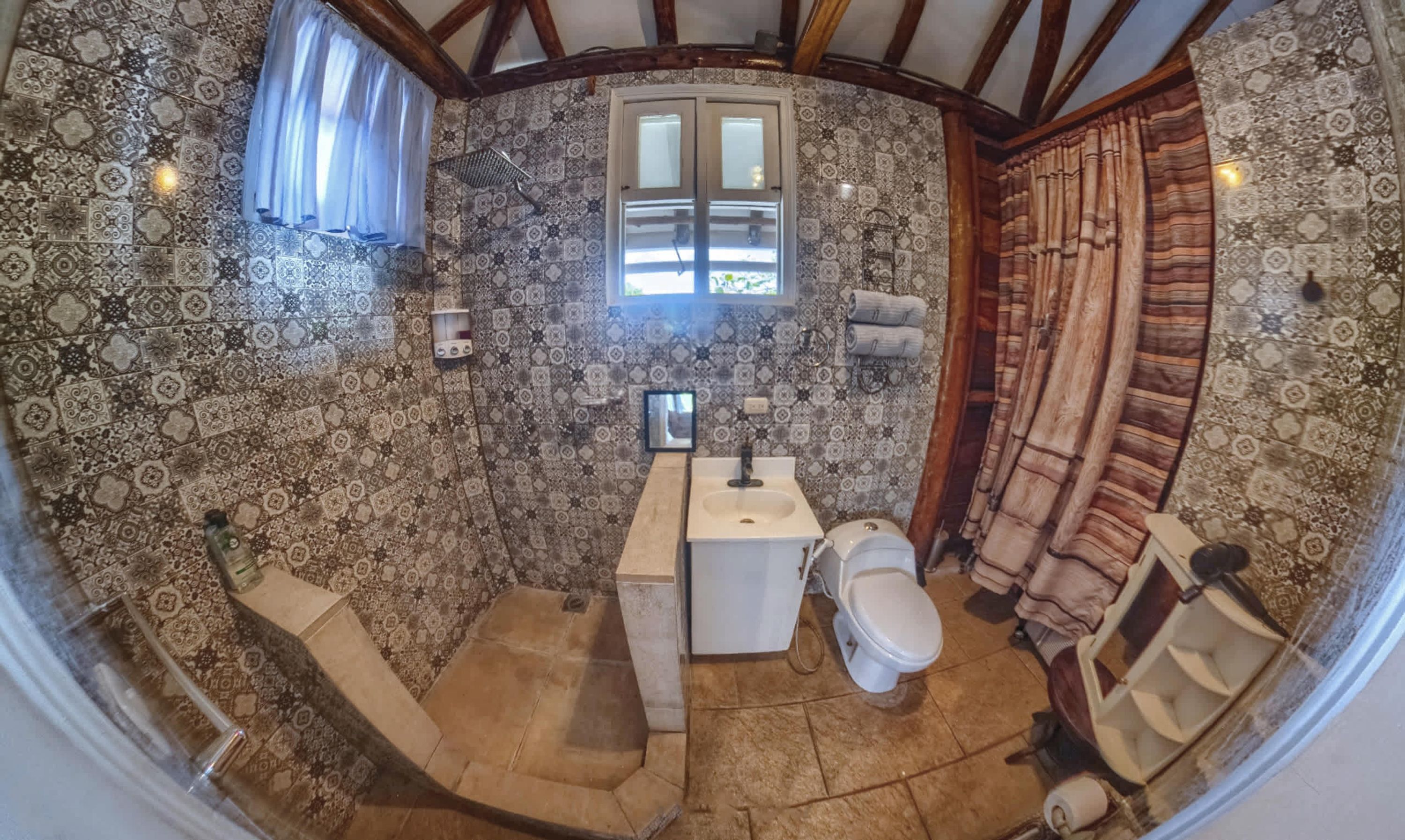 Un baño con baldosas estampadas, una ventana, un lavamanos y un inodoro.