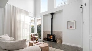 A modern living room with a large sofa, a round wooden coffee table, and a fireplace. - Rubus Green Berry - by Linnaeus Collection (Berry)