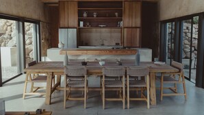 Een moderne keuken met een houten tafel en stoelen, een ingebouwde oven en een achtergrond van een stenen muur.