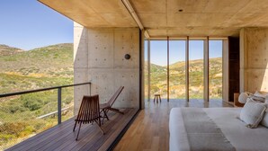 Een moderne kamer met een groot bed, een houten terras en uitzicht op het landschap.
