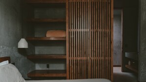 A bedroom with a bed, a nightstand, a wooden shelf unit, and a sliding wooden partition. - Casa Malbec Valle de Guadalupe (Valle de Guadalupe)