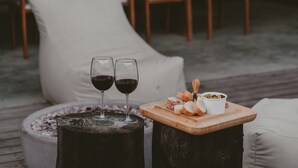 A cozy outdoor seating area with two glasses of red wine, a wooden cutting board with bread and olives, and a white cushion. - Casa Malbec Valle de Guadalupe (Valle de Guadalupe)