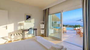 A hotel room with a large bed, a desk, a chair, and a view of the pool and ocean. - VIP Villa Panoramic Seaview Close to Beaches (Ermionida)