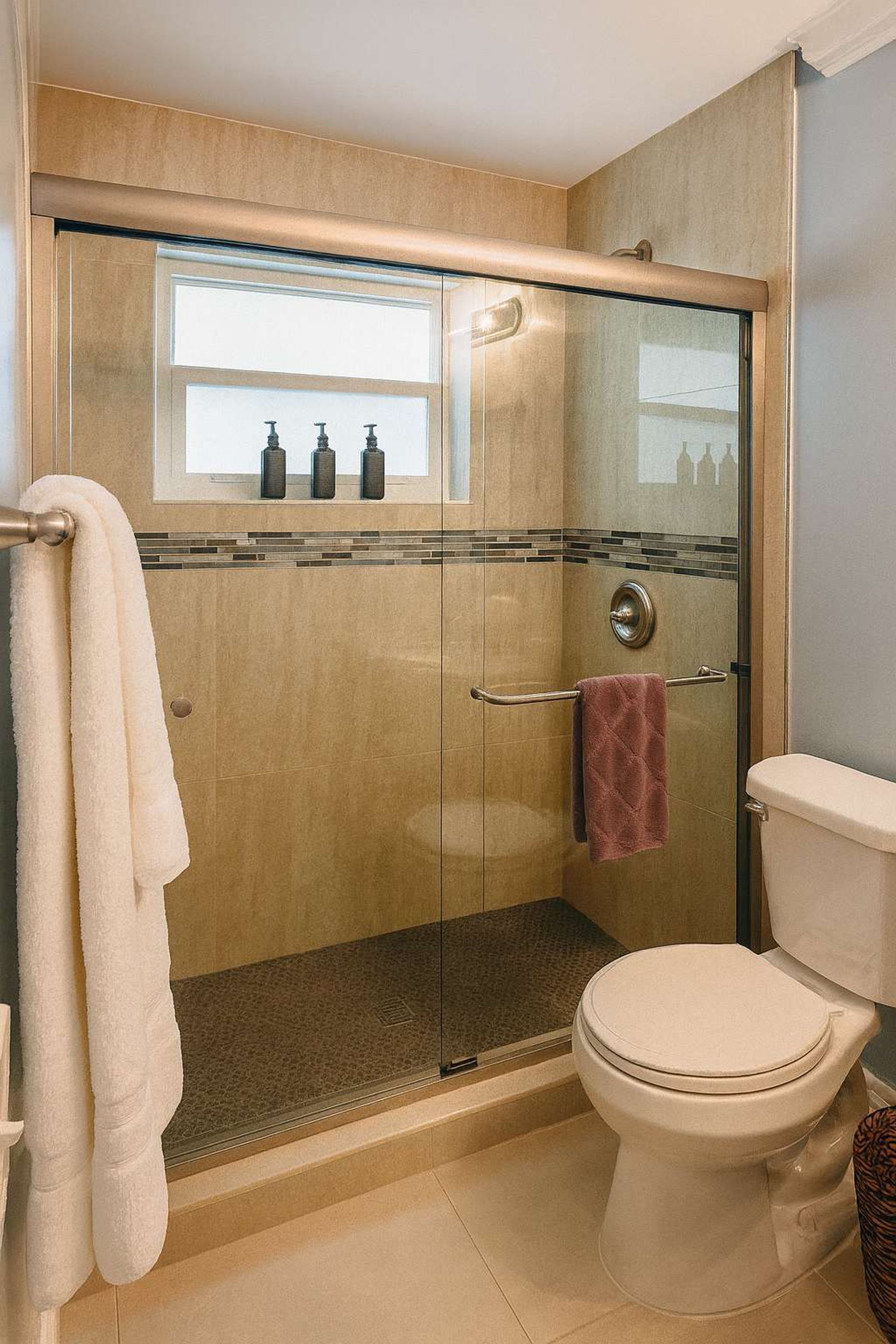 Une salle de bain moderne avec une douche à parois de verre, des toilettes et un porte-serviettes.