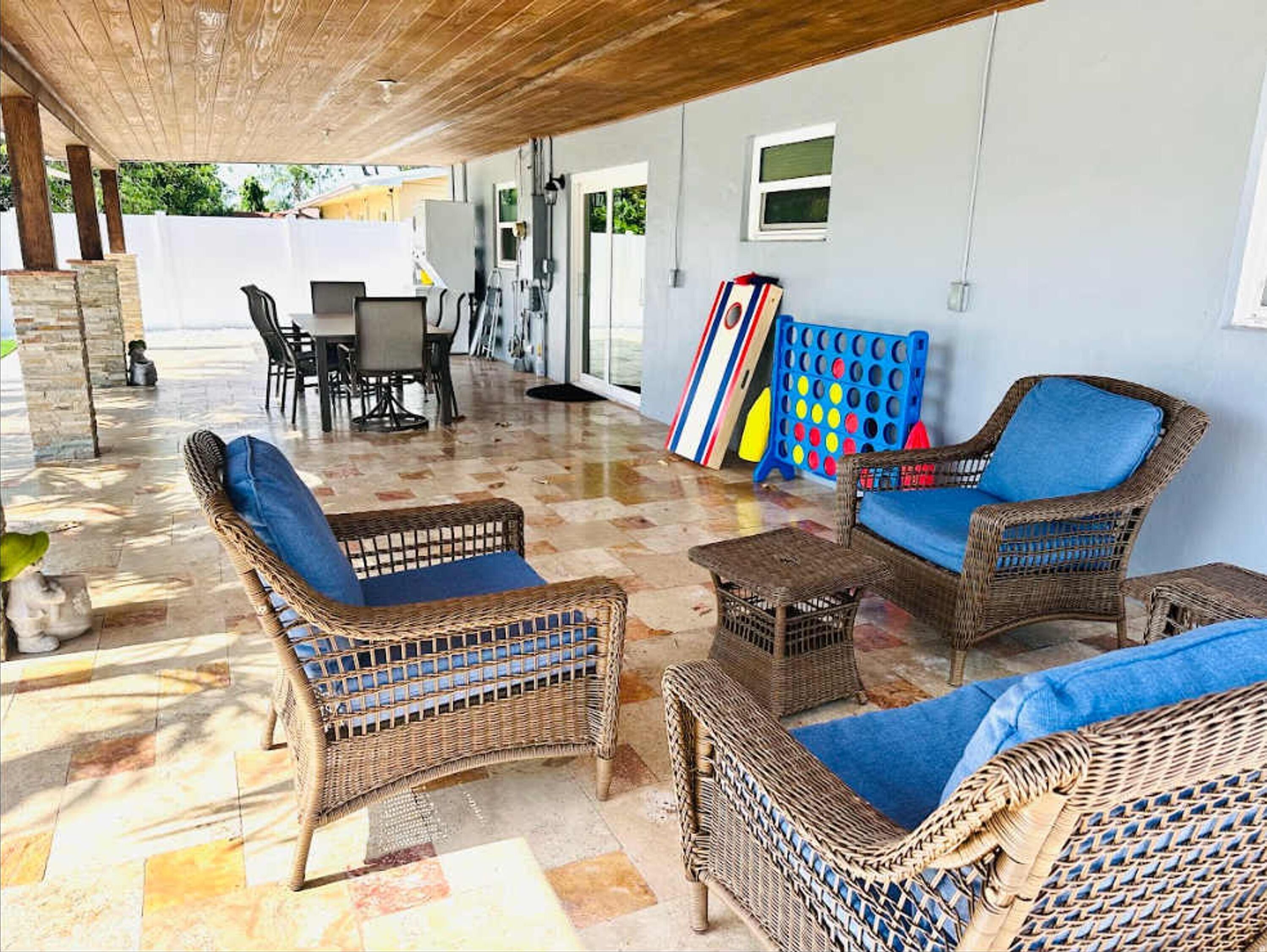 A covered outdoor seating area with wicker furniture and a checkered floor.