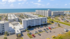 A coastal hotel with multiple buildings, a parking lot, and a beach view. - Good Vibes - The Affordable Beach Vacay (Gulf Shores)