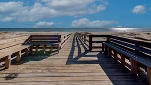 A wooden boardwalk leading to a beach with a clear sky and clouds. - Good Vibes - The Affordable Beach Vacay (Gulf Shores)