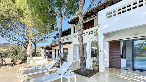 Eine moderne Villa mit Poolbereich, Sitzgelegenheiten im Freien und einer überdachten Terrasse.