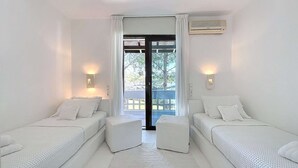 Ein Zimmer mit zwei weißen Betten, einem großen Fenster mit Vorhängen und einer Klimaanlage an der Wand.