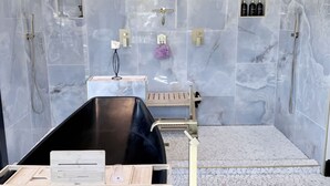 A modern bathroom with a freestanding bathtub, a shower area, and a vanity with a mirror. - Southern Charm House Min From Shopping Beaches (Fairhope)