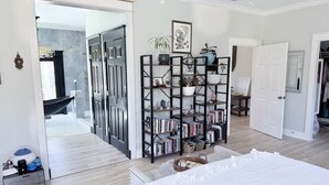 A bedroom with a large bed, a bookshelf, and a bathroom visible through an open door. - Southern Charm House Min From Shopping Beaches (Fairhope)
