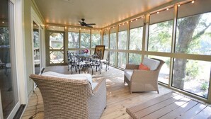 A covered patio area with wicker furniture, a dining table, and string lights. - The Breeze in Seabrook Island (Seabrook Island)