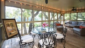 A covered patio with a glass table surrounded by metal chairs, a ceiling fan, and a sofa with cushions. - The Breeze in Seabrook Island (Seabrook Island)
