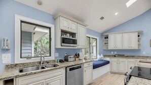 Una cocina moderna con armarios blancos, encimeras de granito, lavavajillas y horno empotrado.