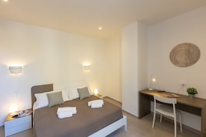 Um quarto moderno com cama, mesas de cabeceira, escrivaninha e cadeira.