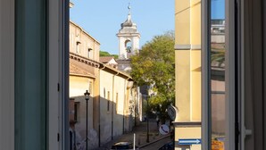 Una calle estrecha con edificios históricos, una torre de campanas y cielo despejado.