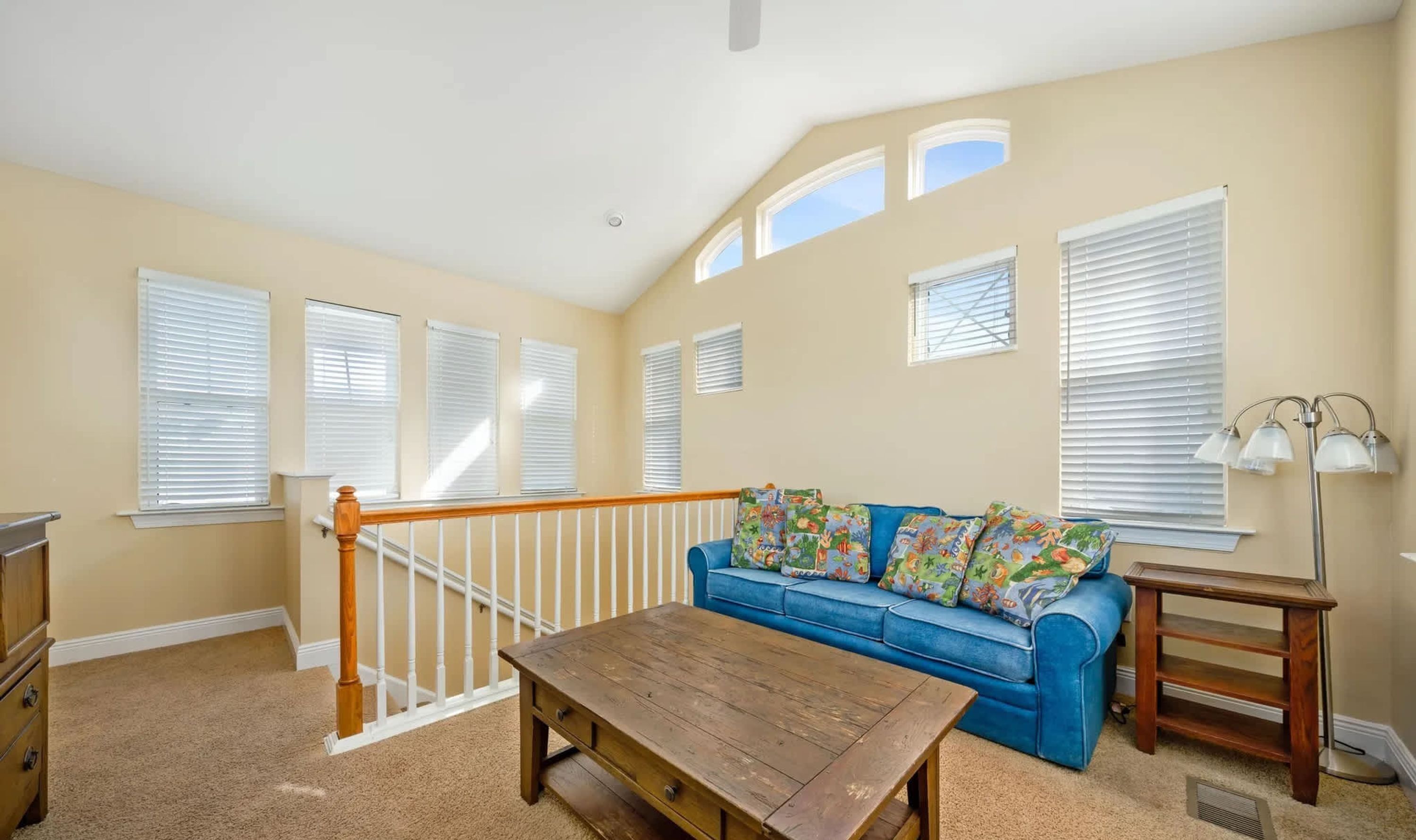 A living room with a blue sofa, wooden coffee table, and a lamp.