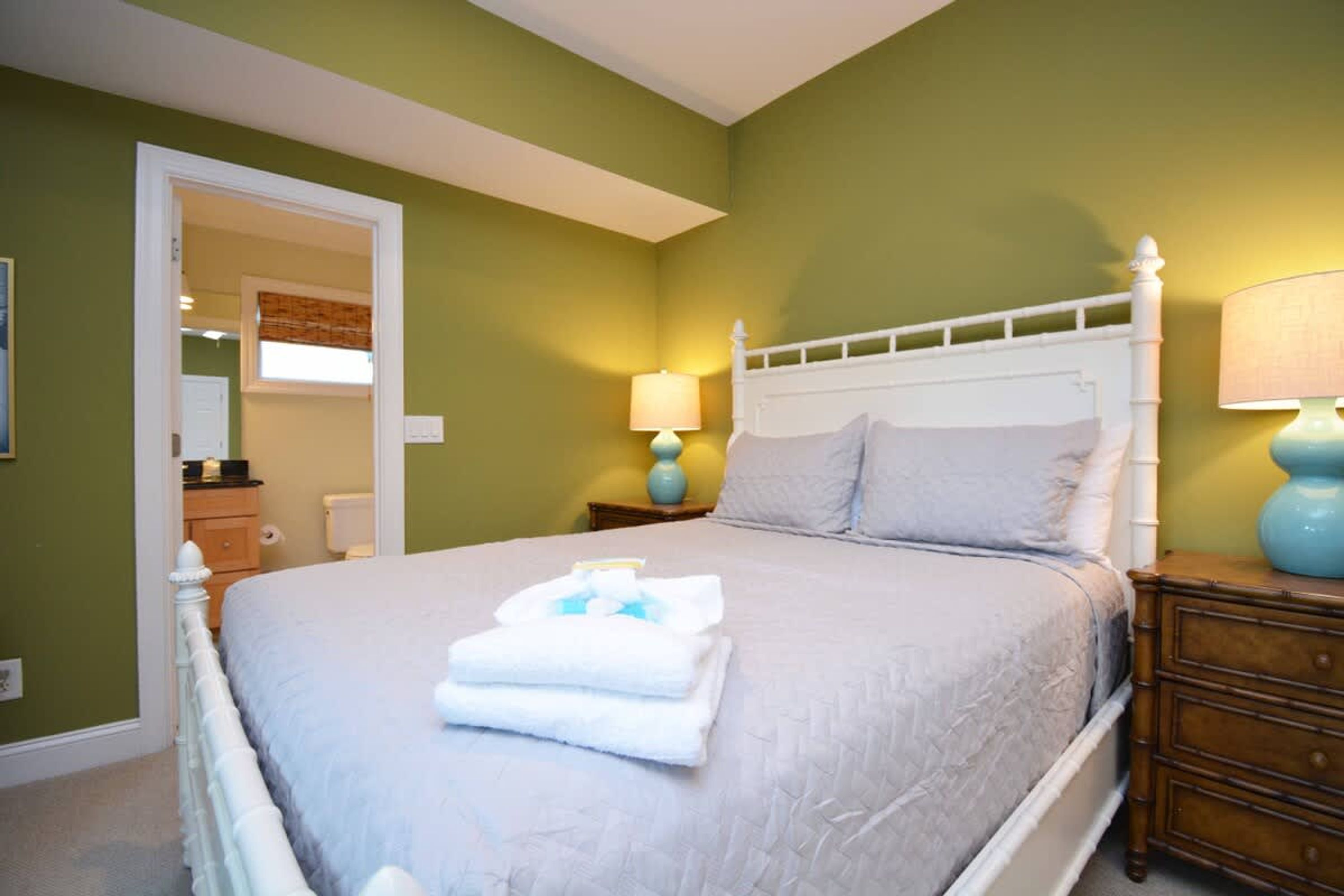 A neatly made bed with folded towels, a white headboard, and two bedside lamps.