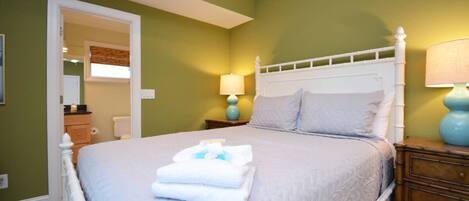 A neatly made bed with folded towels, a white headboard, and two bedside lamps.